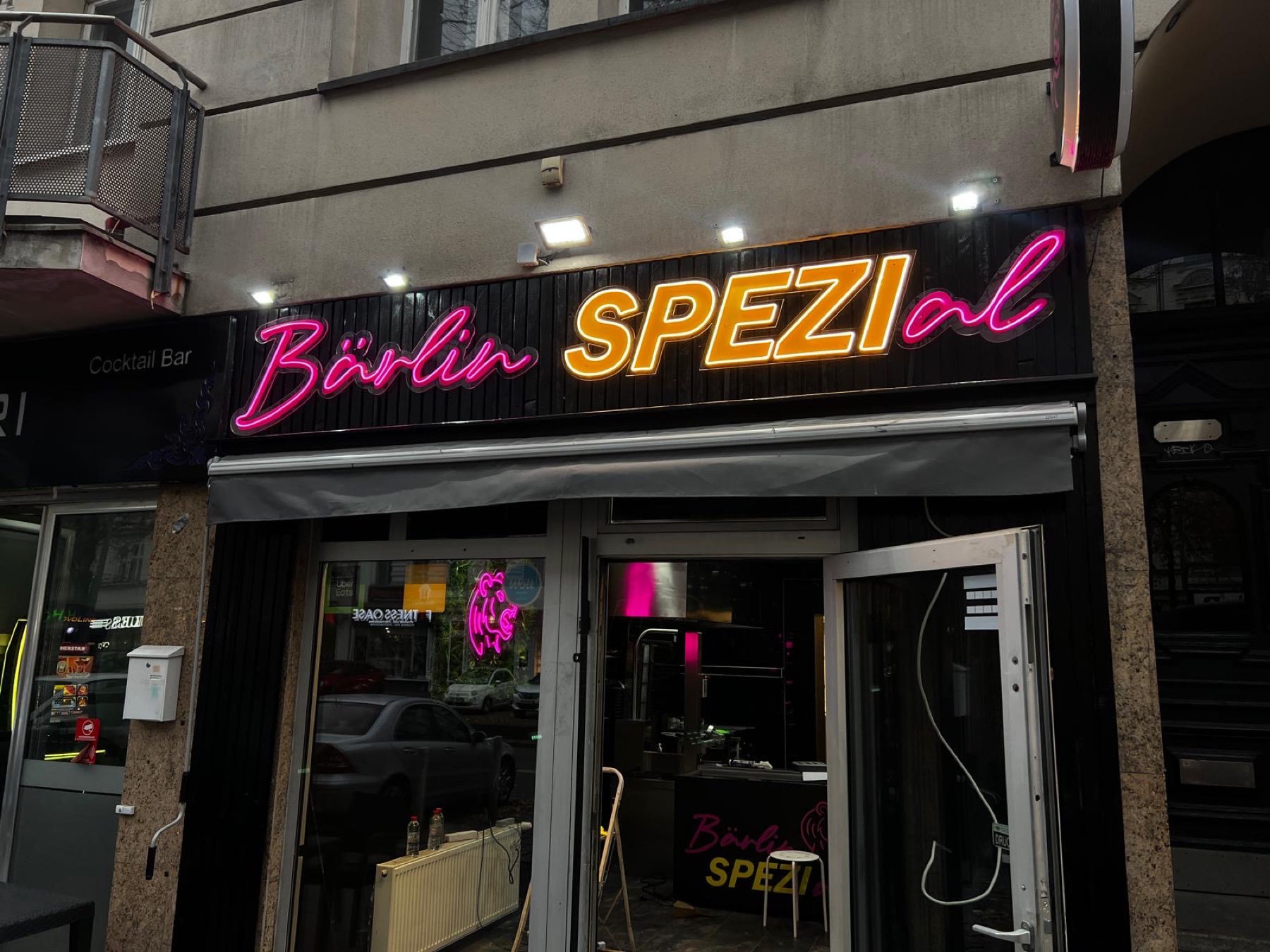 Neon-Schriftzug Bärlin Spezial in Pink und Orange über einem Ladeneingang